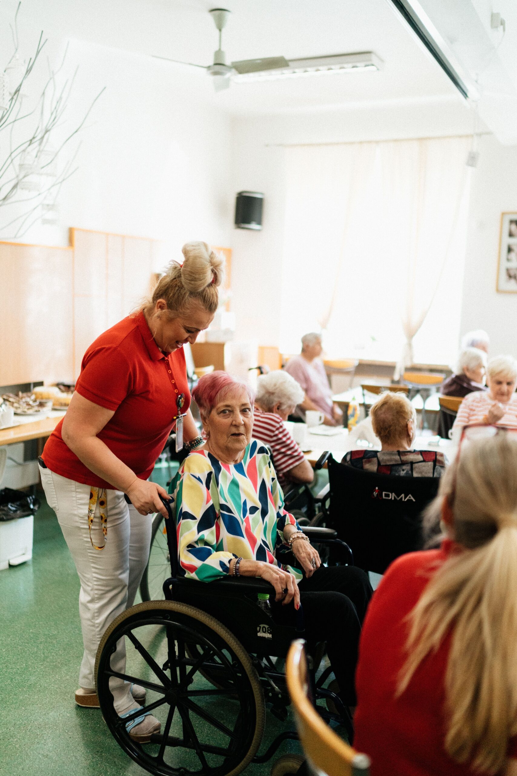 Woman in a red shirt speaking with older adults around a table at a community gathering.